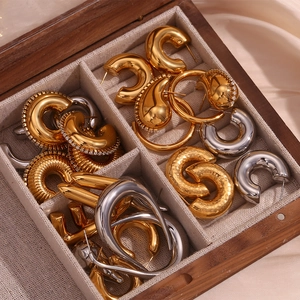 Détail des boucles d'oreilles goutte évidées en or 18K et argent dans un écrin en bois