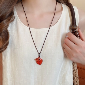 Close-up of heart-shaped natural stone pendant on a woven brown cord necklace