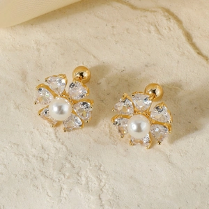 Elegant gold flower stud earrings with white pearl center and zircon petals on stone background