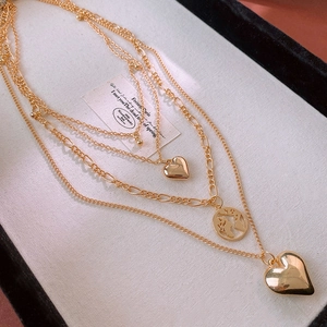 Close-up of layered gold necklace featuring heart pendants and a world map charm detail