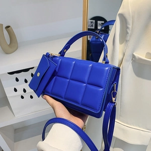 Detailed close-up of blue quilted handbag with matching mini pouch and silver hardware