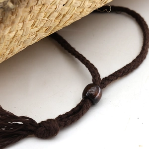 Dettaglio del cappello da cowboy in rafia con cordino intrecciato, perlina in legno e nappa