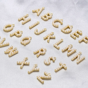 Detailed view of 18K gold plated alphabet pendants with pearls on silk background