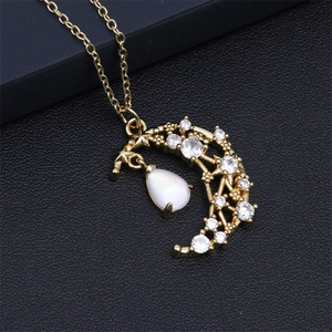 Close-up of gold crescent moon and star necklace with white teardrop gemstones on leather