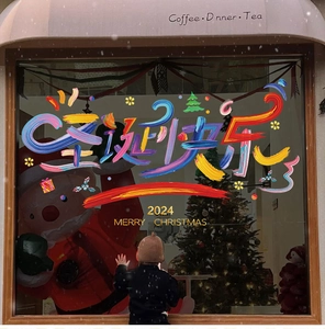 Close-up of 2024 Christmas window stickers with hand-painted artistic lettering and snowy scene