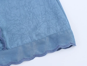 Détail de la robe bleue montrant la texture plissée et la broderie festonnée fine