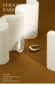 Detail showing polished silver U-shape earrings with S925 hallmark on minimalist props