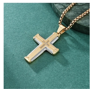 Close-up of two-tone gold and silver cross pendant with small diamonds on marble