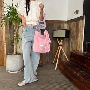 Pink pleated canvas shoulder bag styled with casual outfit in a cozy indoor setting