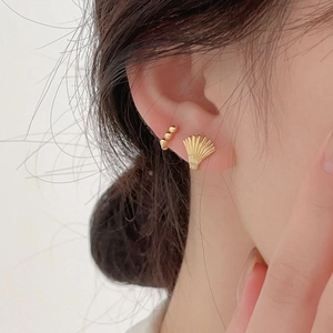 Close-up of elegant gold seashell stud and triple-bead ear cuff worn on model's ear