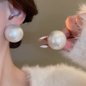 Gros plan de boucles d'oreilles perles géantes blanc crème avec un éclat et une surface lisses