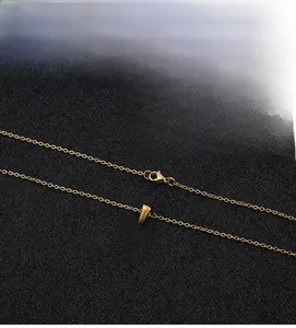 Detailed macro view of gold-plated necklace featuring shell inlay and initial R pendant
