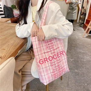 Detail of pink plaid canvas tote bag with red GROCERY text and vegetable list print