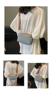 Detail view of a gray canvas crossbody bag with brown adjustable strap and gold hardware