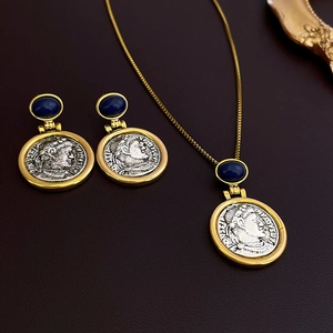 Macro detail of vintage coin jewelry set with blue gemstone in gold frame on leather