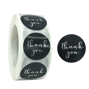 Detail of round black thank you stickers with silver foil stamping on a roll