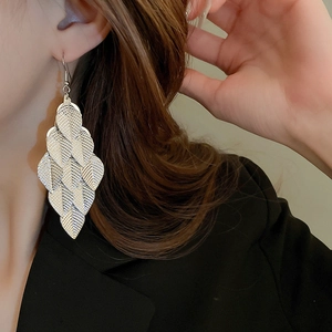 Macro shot of layered leaf sequin tassel earrings in silver and gold on model