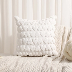 Detailed view of white plush pillow cover with 3D heart pattern on soft knit blanket