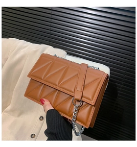 Detail of caramel quilted leather shoulder bag with silver chain strap and flap closure