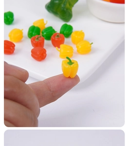 Primer plano macro de mini pimientos coloridos en la punta del dedo para casa de muñecas