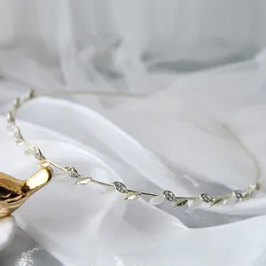 Dettaglio cerchietto foglia argento con strass scintillanti su tessuto bianco
