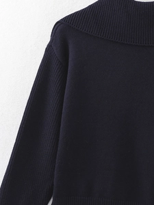 Detailed macro view showing the thick ribbed knit texture and lapel collar of the dark sweater
