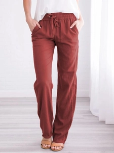 Détail du pantalon en lin brique montrant la taille à cordon et la texture du tissu