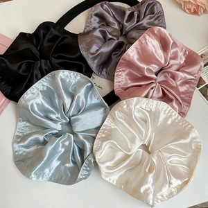 Flat lay of five large satin scrunchies in neutral colors like pink, blue and grey