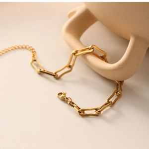 Detail of 18k gold plated stainless steel paperclip chain with lobster clasp on ceramic