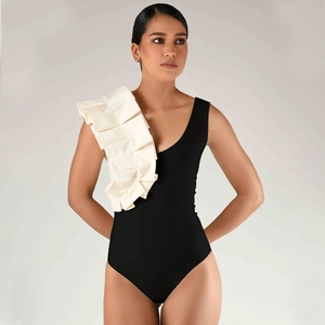 Detail of elegant one-shoulder swimsuit with large off-white ruffle and black V-neckline