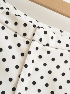 Detailed view of white polka dot shorts with high waist design and wooden hanger