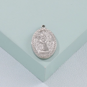 Oval silver religious pendant with embossed holy figure on light green display stand