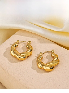 Détail de boucles d'oreilles créoles torsadées plaquées or 18 carats sur soie
