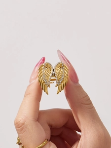 Detail of gold wing ring with sparkling rhinestones held by a manicured hand