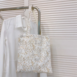 Detail of floral rabbit pattern on cream cotton tote bag hanging on metal hanger