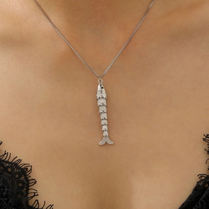 Detailed close-up of a silver fishbone pendant necklace with a green gemstone eye on a model