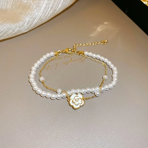 Détail d'un élégant bracelet de perles à double rangée avec pendentif camélia doré