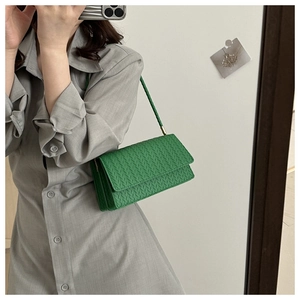 Detail of green woven crossbody bag with matching shoulder strap on grey dress