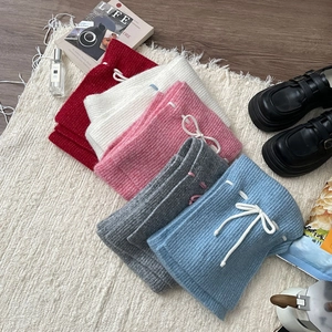 Flat lay of colorful knit shorts with drawstring waist on a soft white carpet background