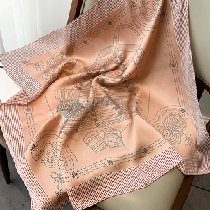 Detail of pink satin scarf with polka dot and equestrian harness patterns on a chair