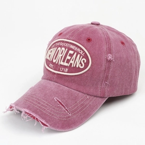 Close-up of pink distressed cotton baseball cap with New Orleans embroidery and torn details