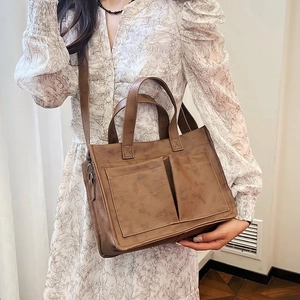 Close-up of brown vintage tote bag featuring symmetrical front pockets and adjustable strap