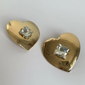 Macro shot of gold heart earrings with center-set square cubic zirconia and mirror finish