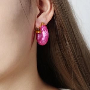 Chic purple resin C-shaped hoop earrings with gold metallic clips worn by a model