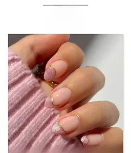 Detail of short almond press-on nails with nude pink glitter and gold wavy line