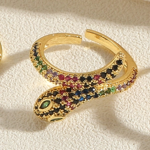 Macro view of gold snake ring featuring vibrant multi-color zircon inlay and green stone eyes