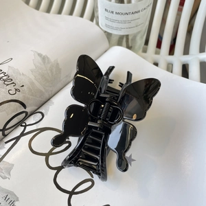 Elegant glossy black butterfly hair claw clip for women on a minimalist lifestyle background