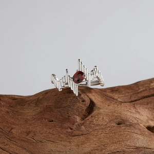 Macro view of an irregular silver ring with red garnet on natural wood background