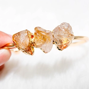 Macro shot of gold-plated bracelet with three raw yellow citrine stones on white fur