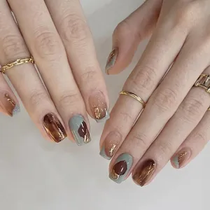 Unghie finte ambra marrone e verde salvia con accenti in foglia d'oro, forma corta quadra